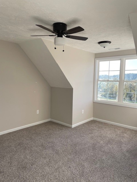 bonus room featuring ceiling fan, a textured ceiling, vaulted ceiling, and carpet floors