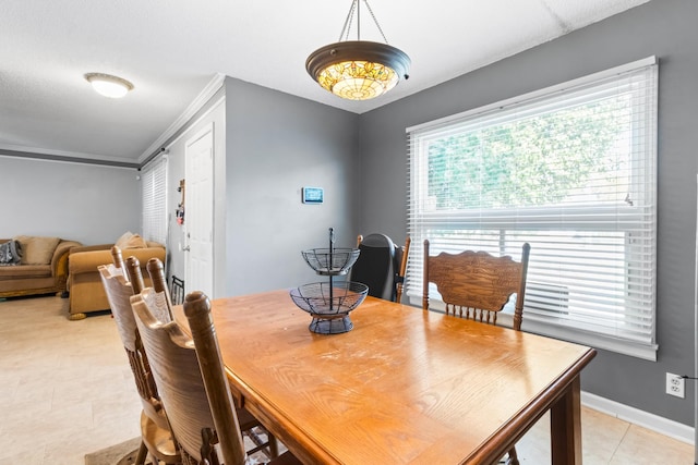 dining room featuring baseboards, ornamental molding, and light tile patterned flooring