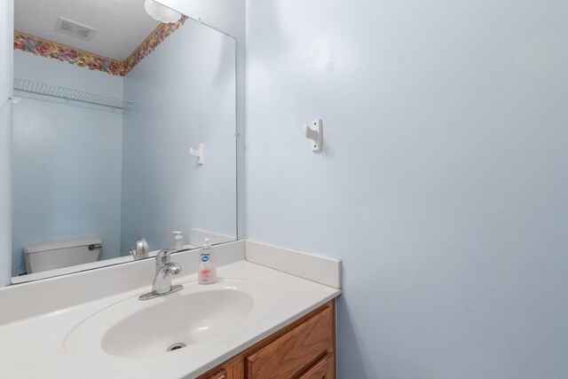 bathroom featuring vanity, toilet, and a textured ceiling