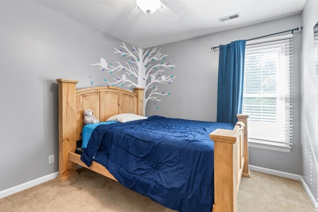 carpeted bedroom featuring multiple windows, a textured ceiling, and ceiling fan