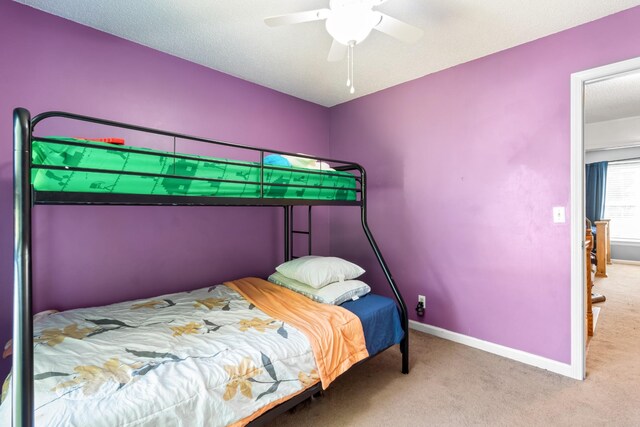 bedroom with ceiling fan, carpet, and a textured ceiling