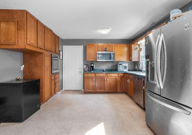 kitchen featuring brown cabinets, appliances with stainless steel finishes, and a sink