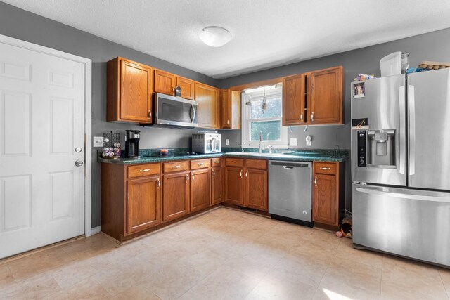 kitchen featuring appliances with stainless steel finishes, a textured ceiling, and sink