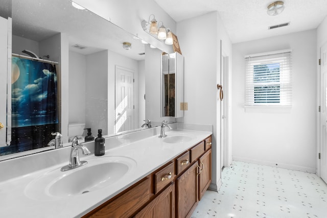 bathroom featuring toilet, a textured ceiling, and vanity