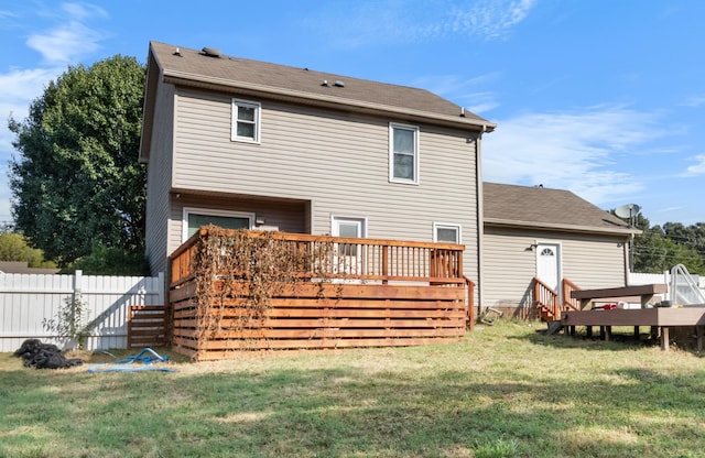 rear view of property with a lawn, a deck, and fence