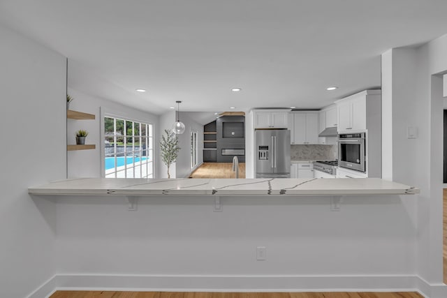 kitchen featuring appliances with stainless steel finishes, kitchen peninsula, light hardwood / wood-style floors, and a breakfast bar