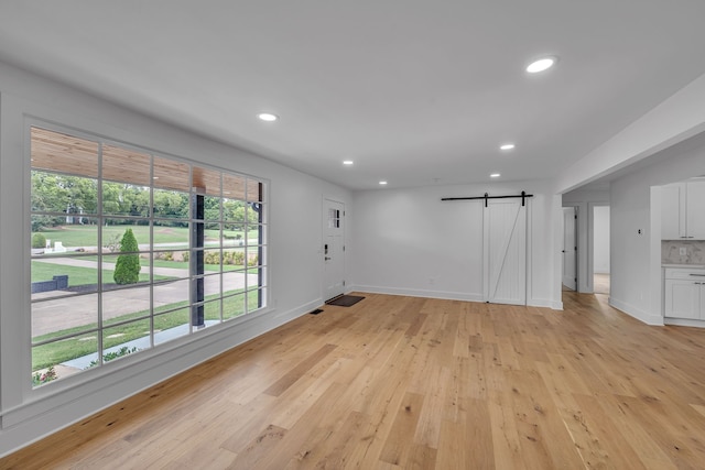 unfurnished living room featuring a barn door and light wood-type flooring