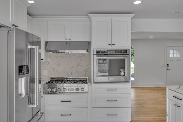 kitchen featuring stainless steel appliances, white cabinetry, tasteful backsplash, and light hardwood / wood-style flooring