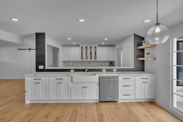 kitchen with light stone counters, white cabinets, sink, light hardwood / wood-style flooring, and dishwasher