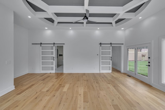 unfurnished living room featuring light hardwood / wood-style floors, coffered ceiling, a barn door, beam ceiling, and ceiling fan