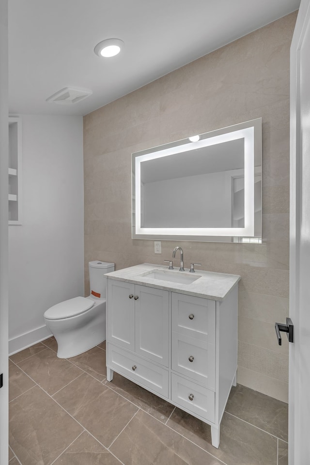 bathroom with vanity, tile walls, toilet, and tile patterned floors