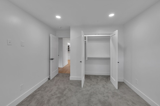 unfurnished bedroom with light carpet and a closet