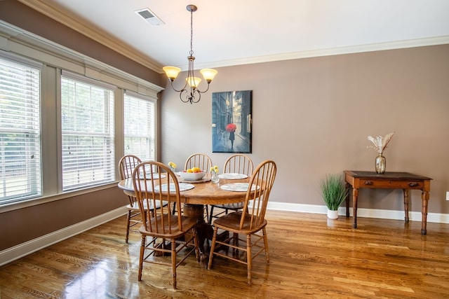 dining space with a wealth of natural light, hardwood / wood-style flooring, a notable chandelier, and ornamental molding