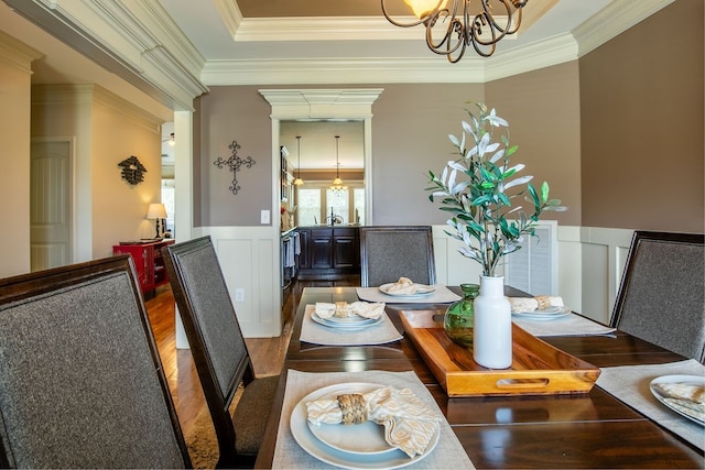 dining area with wood-type flooring, a notable chandelier, and ornamental molding