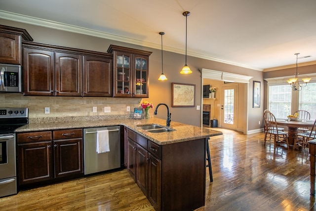 kitchen featuring an inviting chandelier, a kitchen breakfast bar, stainless steel appliances, sink, and kitchen peninsula