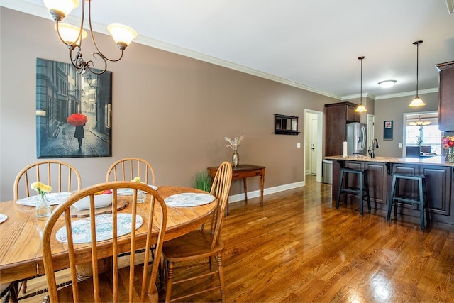 dining space featuring crown molding, dark hardwood / wood-style flooring, sink, and a notable chandelier