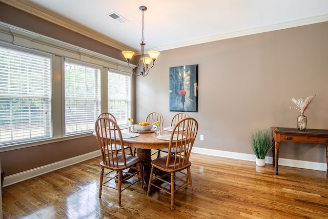 dining space with a notable chandelier, wood-type flooring, plenty of natural light, and crown molding