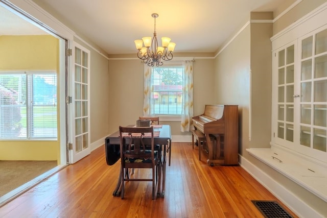 dining space featuring ornamental molding, wood-type flooring, and an inviting chandelier