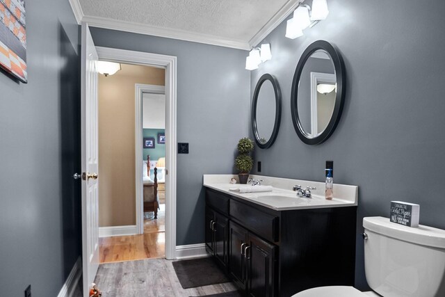 bathroom with hardwood / wood-style flooring, crown molding, a textured ceiling, toilet, and vanity