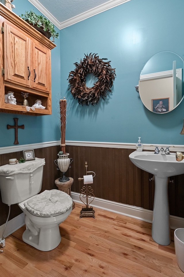 bathroom featuring wood-type flooring, toilet, wooden walls, and crown molding