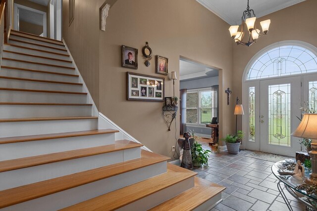 entrance foyer with a high ceiling, a chandelier, and crown molding