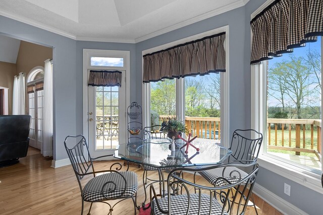 dining space with a wealth of natural light, ornamental molding, and hardwood / wood-style flooring