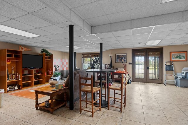 interior space with a paneled ceiling, light tile patterned floors, and french doors