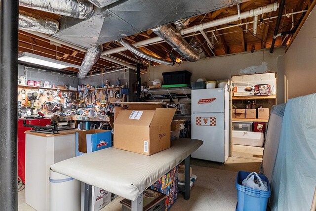 basement featuring white fridge and a workshop area