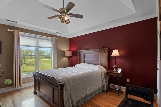 bedroom featuring ornamental molding, a textured ceiling, light hardwood / wood-style flooring, and ceiling fan