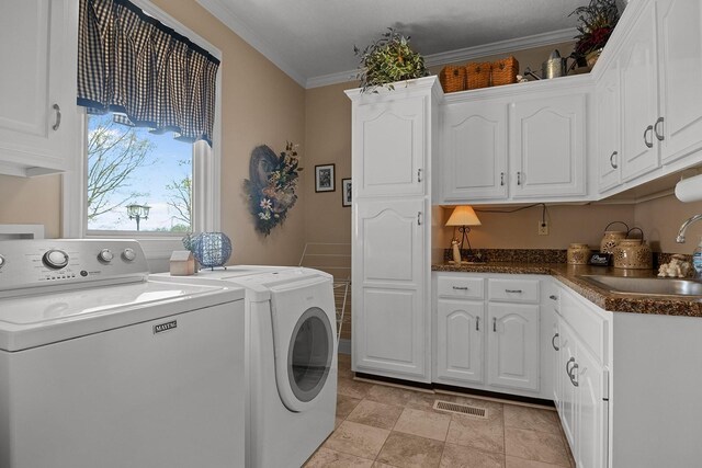 washroom with cabinets, ornamental molding, washer and clothes dryer, and sink