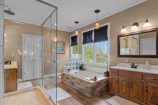 bathroom with wood-type flooring, shower with separate bathtub, crown molding, and vanity