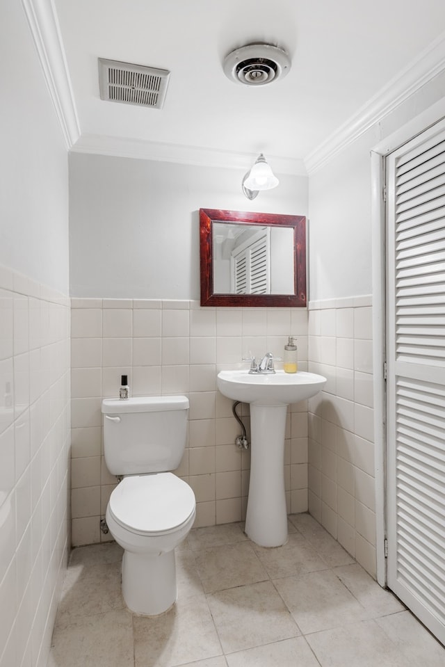 bathroom with crown molding, tile walls, toilet, and tile patterned flooring