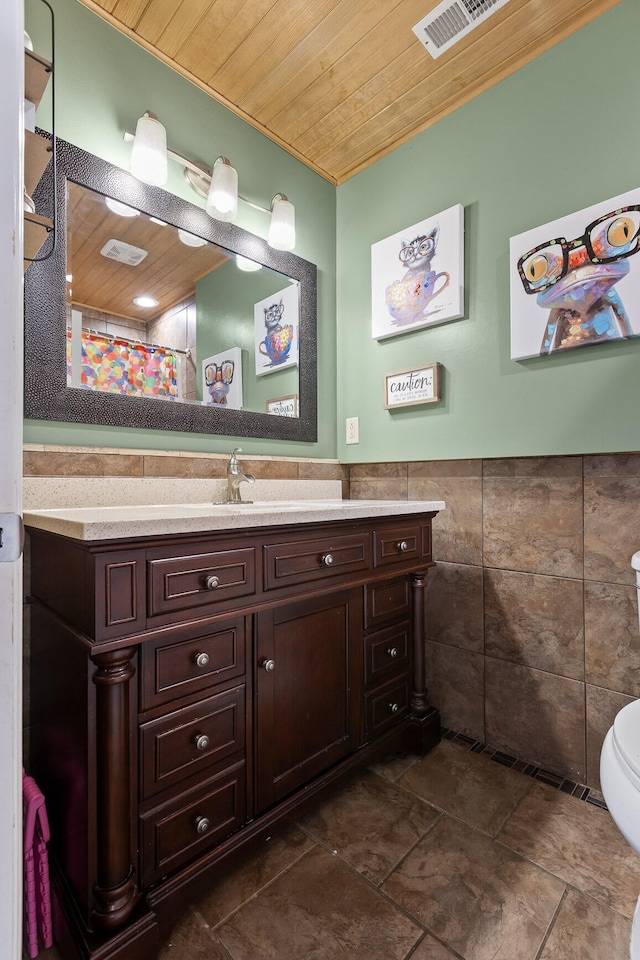 bathroom featuring wood ceiling, tile walls, toilet, and vanity