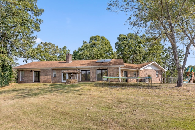 ranch-style house featuring a playground, solar panels, and a front yard