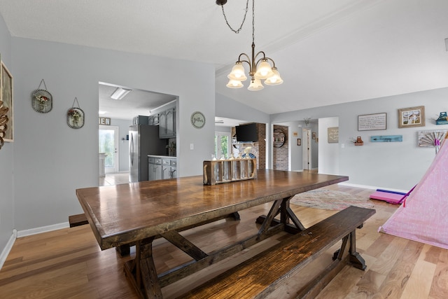 dining area with light hardwood / wood-style flooring, vaulted ceiling, and a chandelier