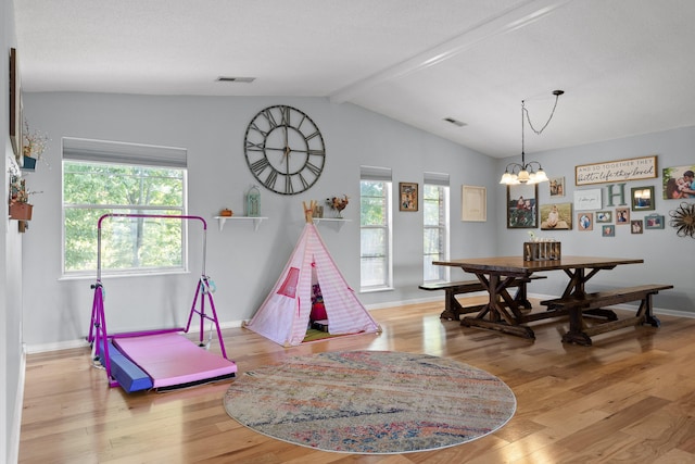 playroom featuring a textured ceiling, light hardwood / wood-style floors, a notable chandelier, and vaulted ceiling with beams