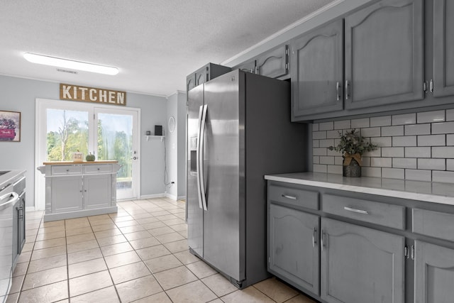 kitchen featuring a textured ceiling, gray cabinetry, decorative backsplash, and stainless steel refrigerator with ice dispenser