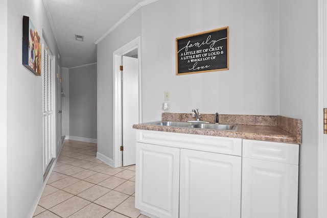 kitchen with crown molding, light tile patterned floors, white cabinetry, and sink