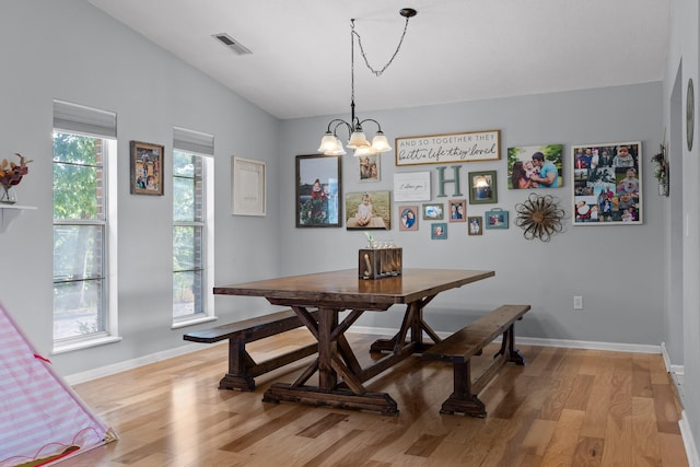 dining area featuring lofted ceiling, a notable chandelier, and light wood-type flooring