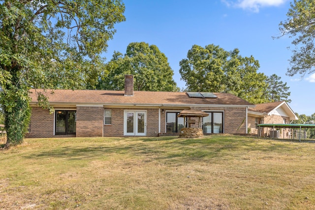 back of house featuring a lawn, solar panels, and french doors