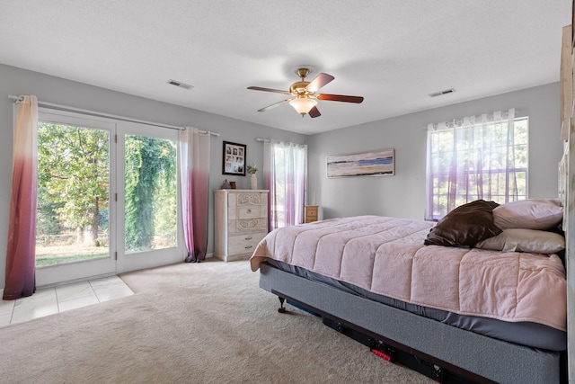 carpeted bedroom with access to exterior, ceiling fan, and multiple windows