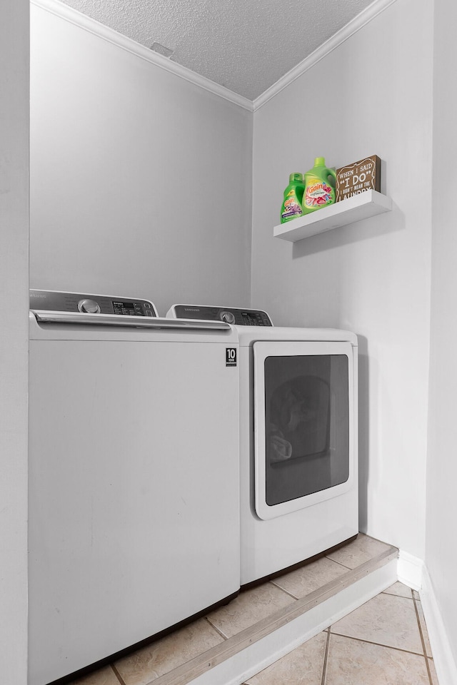 washroom featuring crown molding, a textured ceiling, washing machine and dryer, and light tile patterned floors