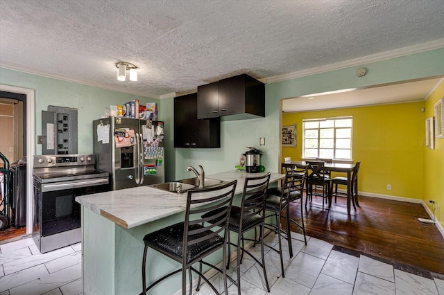 kitchen with crown molding, light hardwood / wood-style flooring, appliances with stainless steel finishes, a breakfast bar area, and a textured ceiling