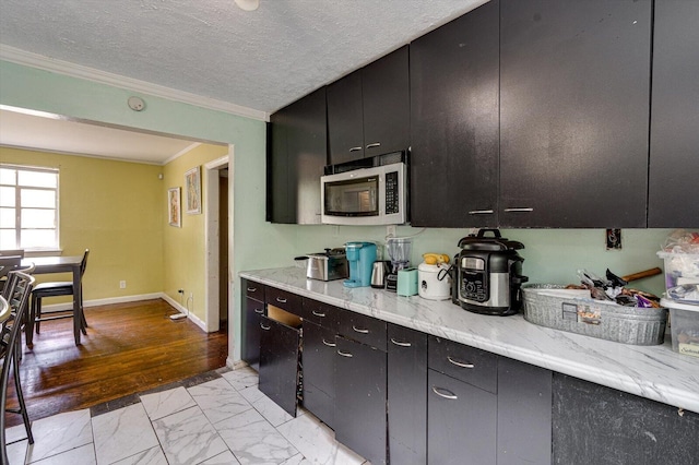 kitchen featuring light stone counters, light hardwood / wood-style floors, a textured ceiling, and ornamental molding