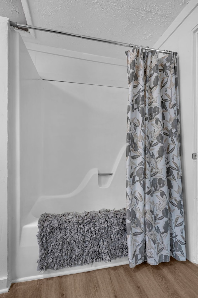 bathroom featuring a textured ceiling, wood-type flooring, and shower / bath combo