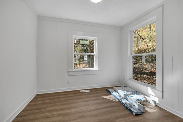 empty room featuring ornamental molding, dark hardwood / wood-style floors, and a textured ceiling