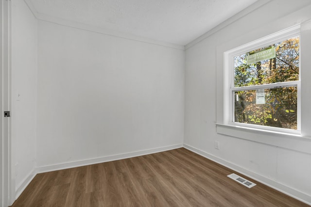 unfurnished room with hardwood / wood-style flooring, ornamental molding, and a textured ceiling