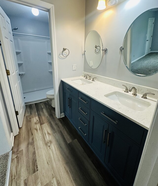 bathroom with a shower, hardwood / wood-style floors, toilet, and vanity