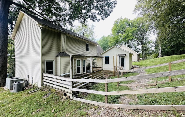 rear view of house featuring a wooden deck, a lawn, and cooling unit