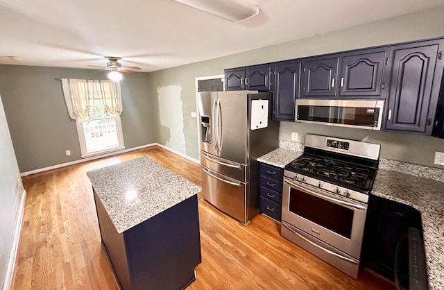 kitchen featuring light stone countertops, stainless steel appliances, ceiling fan, and light hardwood / wood-style floors